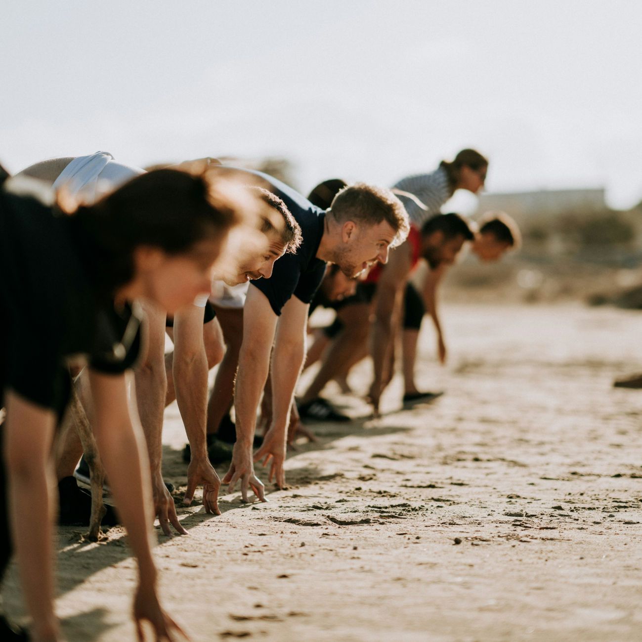 Gruppe Sportler im Freien, die sich in Startposition für einen Sprint vorbereiten