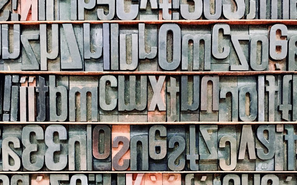 Bleilettern in einem Setzkasten in Zeilenform. Die Buchstaben sind spiegelverkehrt